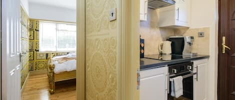 A room with a bed, a kitchen with a stove and cabinets, and a patterned wall.