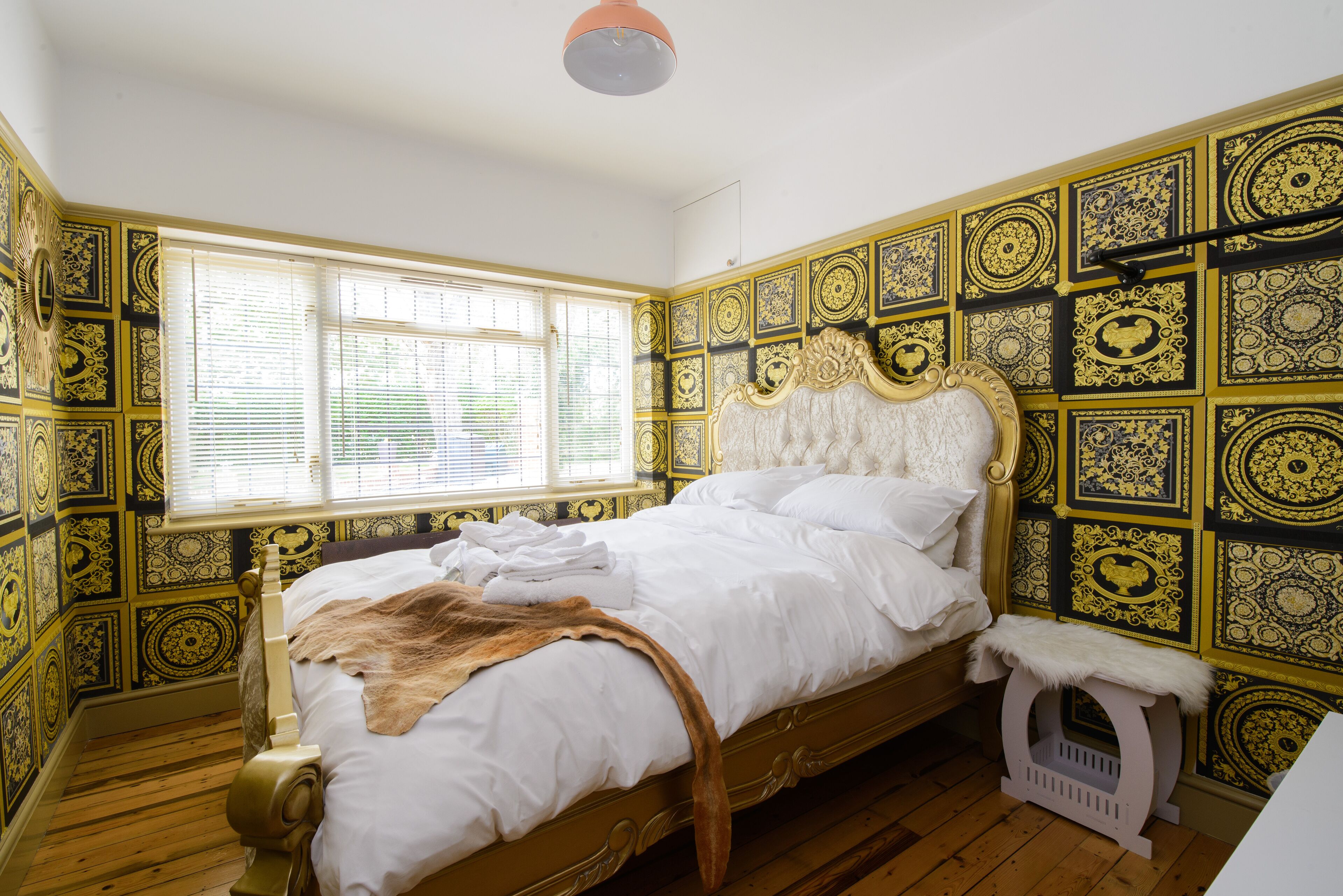 Una habitación con una cama, un ventanal y un papel tapiz estampado.