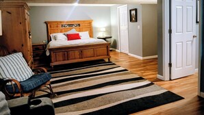 Un dormitorio con una cama de madera, una silla a rayas, un felpudo con estampado de cebra y una puerta blanca.