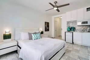 Cozy retreat with a large bed, compact kitchen area, and marble floor.