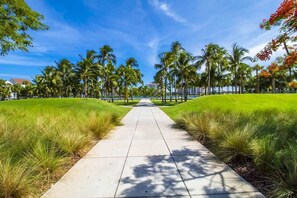 Stroll through lush gardens to a modern building with a flat roof and large windows.