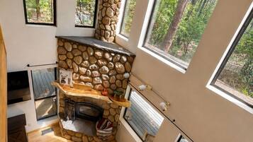 Un interior acogedor con chimenea de piedra, ventanas amplias y suelo de madera.