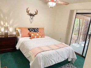 Un dormitorio con cama, una mesita de noche de madera, un adorno en la pared y vistas al exterior.