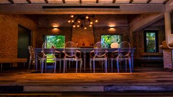 A dining area with a brick wall, a wooden ceiling, and a table with chairs.