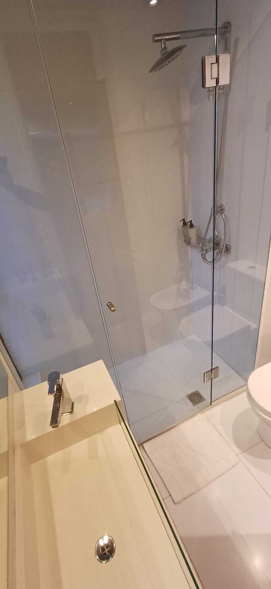A modern bathroom with a glass shower enclosure, a toilet, and a sink.