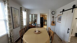 Ein Essbereich mit einem runden Tisch, Stühlen, einer Uhr und einer Gitarre an der Wand.