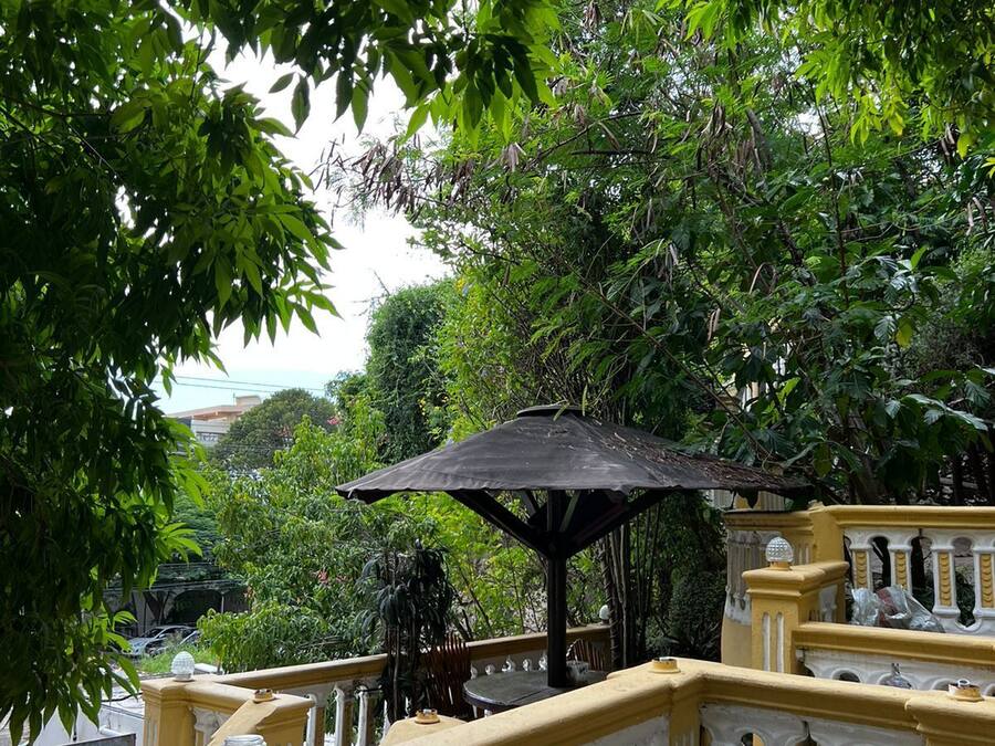 A balcony with a yellow railing, a black umbrella, and two black trash bins.