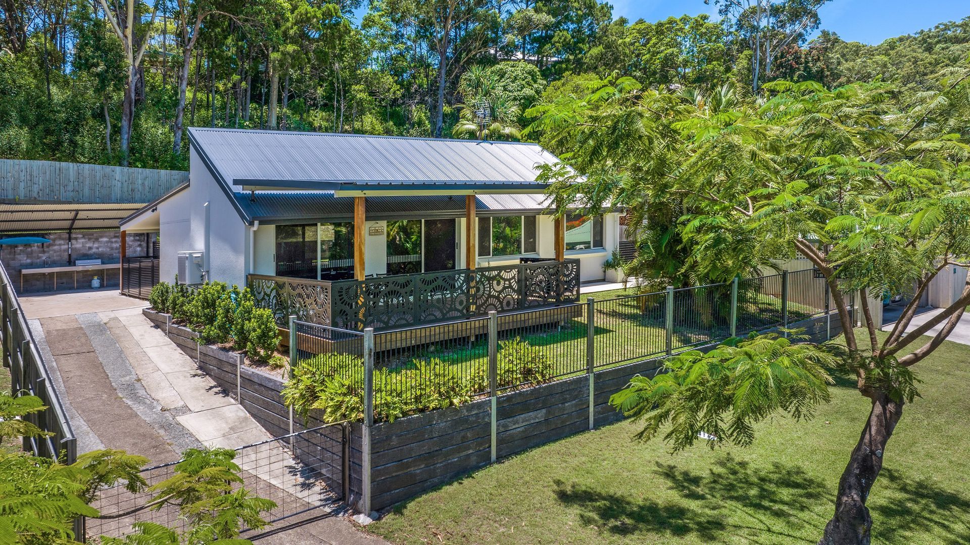 A modern two-story house with a covered patio and a fenced backyard.