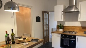 A modern kitchen with a wooden countertop, a gas stove, a dishwasher, and a red chair.