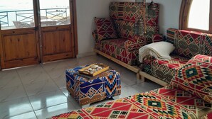 A room with a large arched window, a patterned sofa, a wooden bench, and a tray of snacks. - Tala Boutique Accommodation 14 (Hurghada)