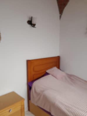 A bedroom with a wooden headboard, a single bed, a nightstand, and a wall-mounted light fixture. - Tala Boutique Accommodation 14 (Hurghada)