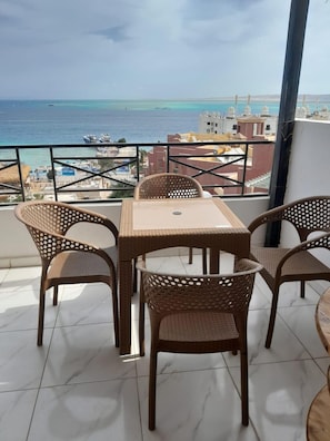 A balcony with wicker furniture, a view of the sea, and buildings in the background. - Tala Boutique Accommodation 14 (Hurghada)