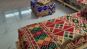 A room with a large window, a sofa, a patterned ottoman, and a decorative lamp. - Tala Boutique Accommodation 14 (Hurghada)