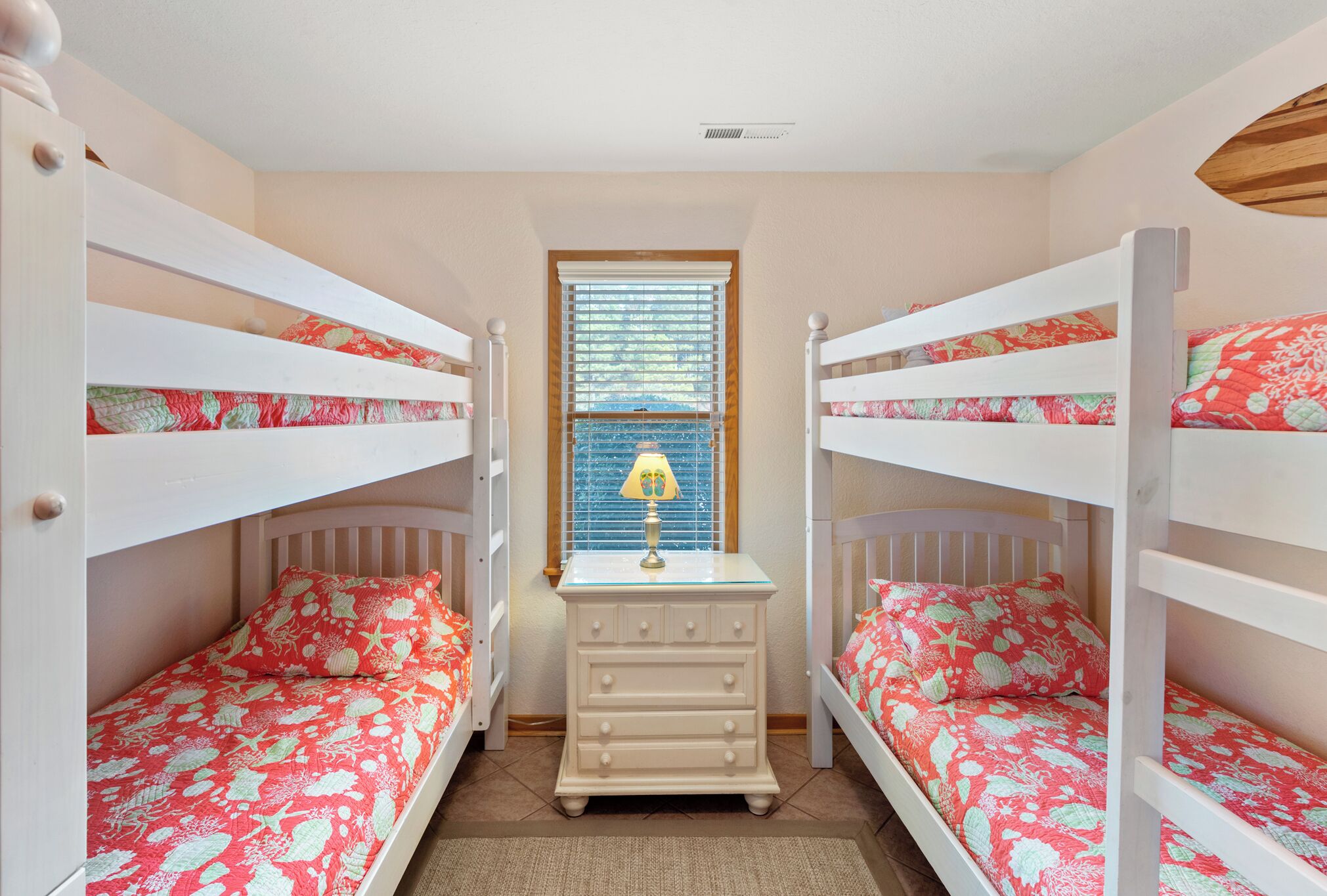 A bedroom with two bunk beds, a dresser, and a window with blinds.