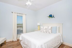 Relax in this serene bedroom with a large bed, nightstand, and table, complete with a ceiling fan and decorative fish.
