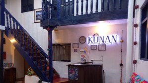 A hotel lobby with a staircase, a reception desk, and a colorful wall decoration. - Kunan Cusco (Cusco)