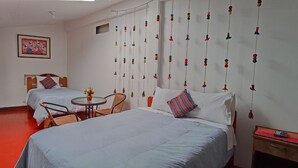 A hotel room with two beds, a small table, and a chair. There is a painting on the wall and a decorative hanging on the right side. - Kunan Cusco (Cusco)