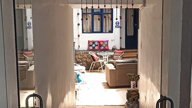 A hallway with patterned tiles leading to a living area with a sofa and decorative items. - Kunan Cusco (Cusco)