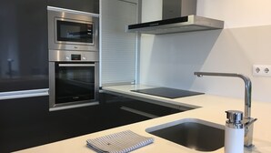 A modern kitchen with built-in appliances, a stainless steel sink, and a clean, minimalist design. - New apartment, high standing, 180º panoramic view of the sea. (Llançà)