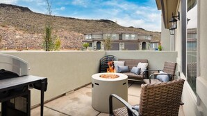 Une terrasse avec des meubles d’extérieur, un foyer et une vue sur une maison en arrière-plan.