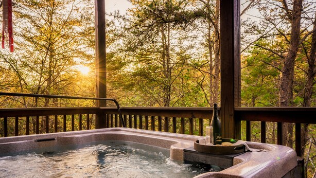 A hot tub with a view of a forested area. - Outdoor movie theater, Fire pit, Hot tub, Game rm, 3Mi to Parkway, Pet friendly! (Pigeon Forge)