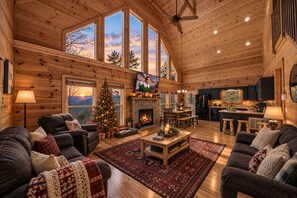A cozy cabin interior with a fireplace, wooden furniture, and a Christmas tree. - Outdoor movie theater, Fire pit, Hot tub, Game rm, 3Mi to Parkway, Pet friendly! (Pigeon Forge)