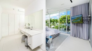 A modern bedroom with a large bed, a vanity with a mirror, and a TV mounted on the wall.