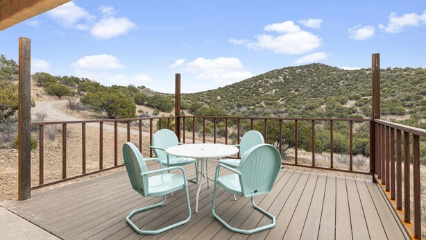 A wooden deck with a table and chairs, overlooking a hilly landscape. - Casa del Norte - Secluded Home in Del Norte Mtns (Alpine)