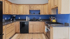 A kitchen with wooden cabinets, a black dishwasher, a stove, and a sink. - Casa del Norte - Secluded Home in Del Norte Mtns (Alpine)