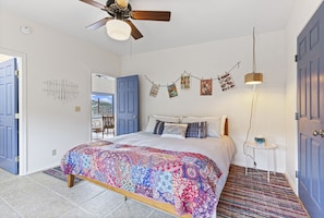 Ein Schlafzimmer mit Bett, Deckenventilator, Wandlampe und einer Tür.