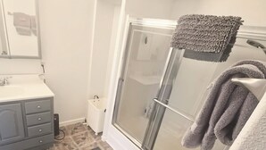 Un baño con ducha, lavamanos y espejo.