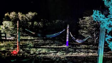 Een nachtelijk buitengebied met verlichte gebouwen en een hangmat.