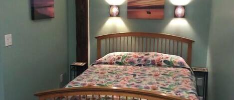 A bedroom with a wooden bed, floral bedding, and two wall-mounted lights.