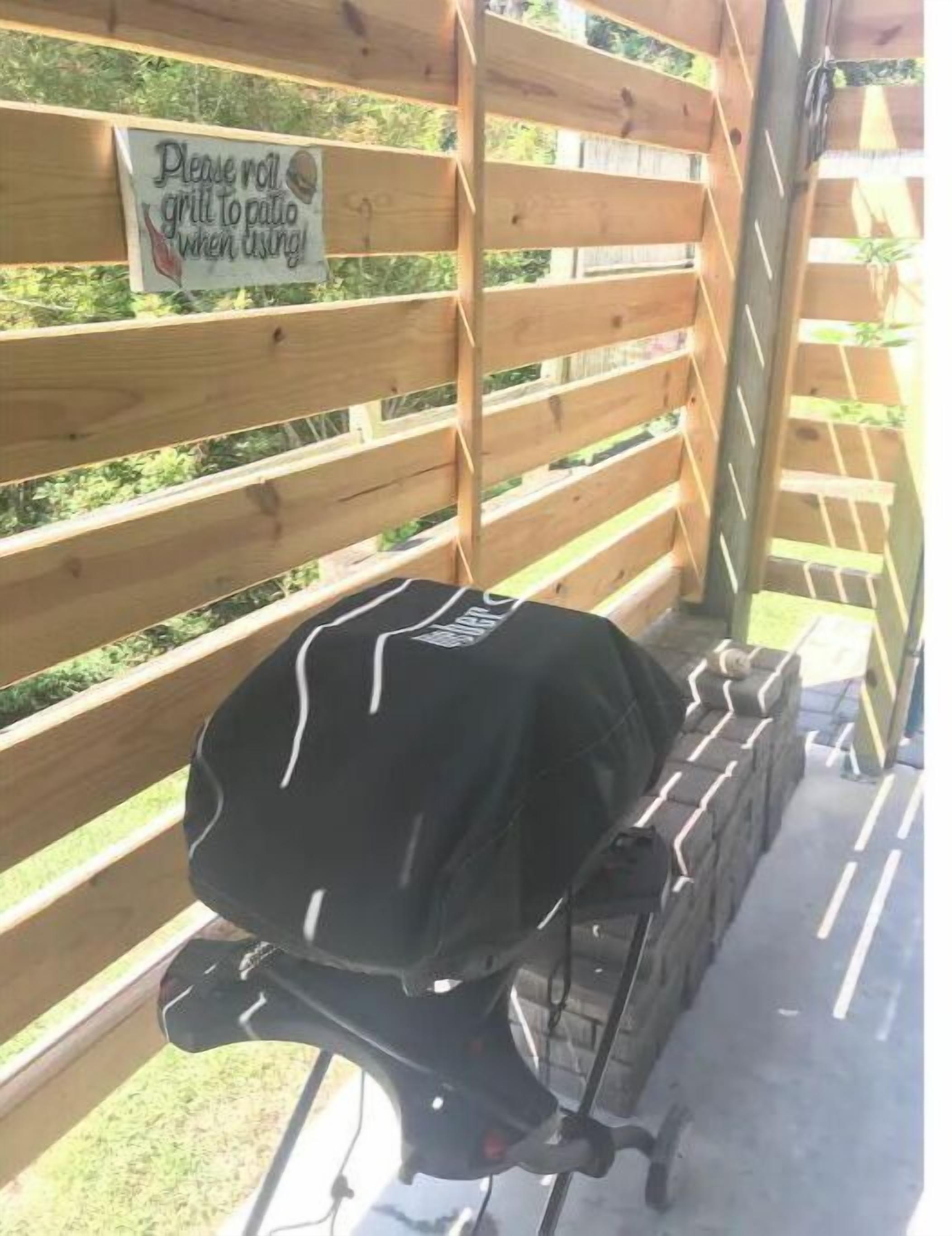 Un barbecue sur une terrasse en bois, avec une pancarte indiquant : « Veuillez déplacer le barbecue sur la terrasse avant de l’utiliser. »