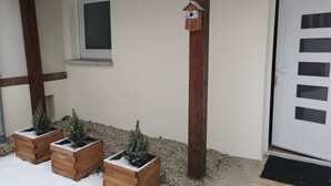 Een gevel met een houten deur, een raam en een vogelhuisje.