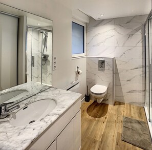 Un baño moderno con un espejo grande, una bañera, un inodoro y una ducha.