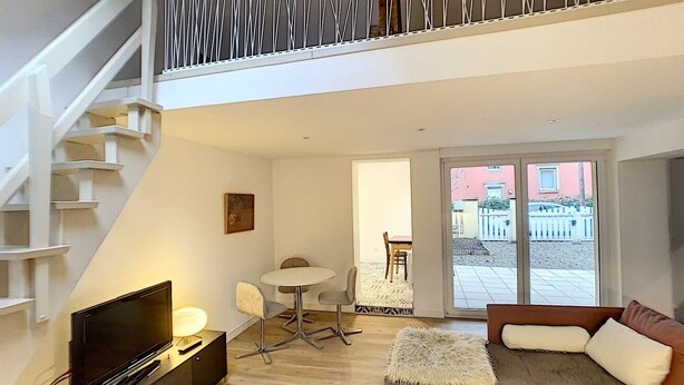 Een moderne woonkamer met een televisie, bank en eethoek.