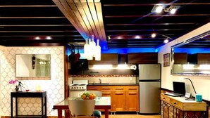 Une cuisine moderne avec des meubles en bois, un réfrigérateur, une cuisinière et un coin repas comprenant une table et des chaises.