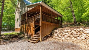 A cabin with a porch, wooden stairs, and a stone wall. - Cabin close to town, private beach, parking & hot tub (Old Forge)