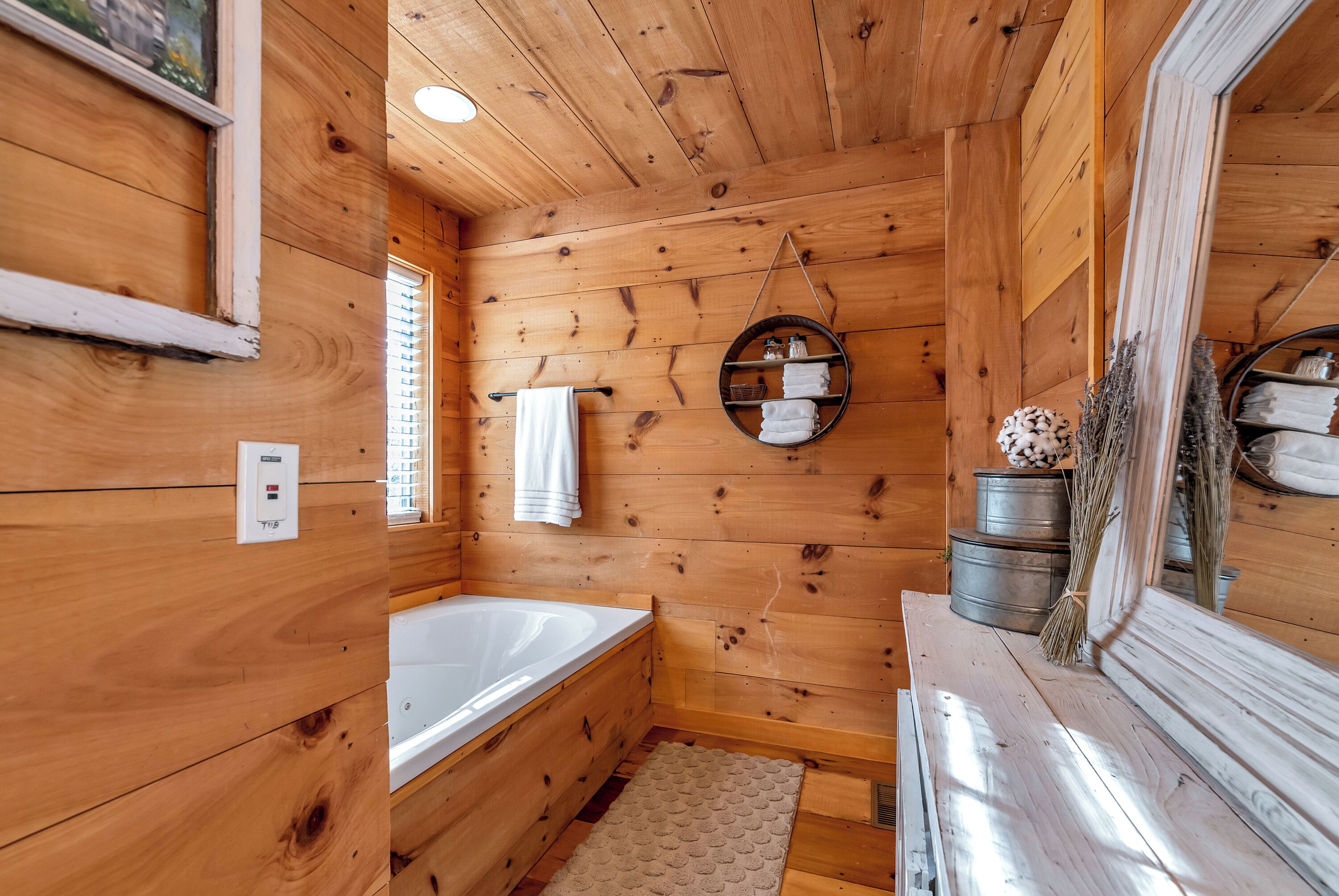 A wooden cabin bathroom with a bathtub, a towel rack, and a mirror.