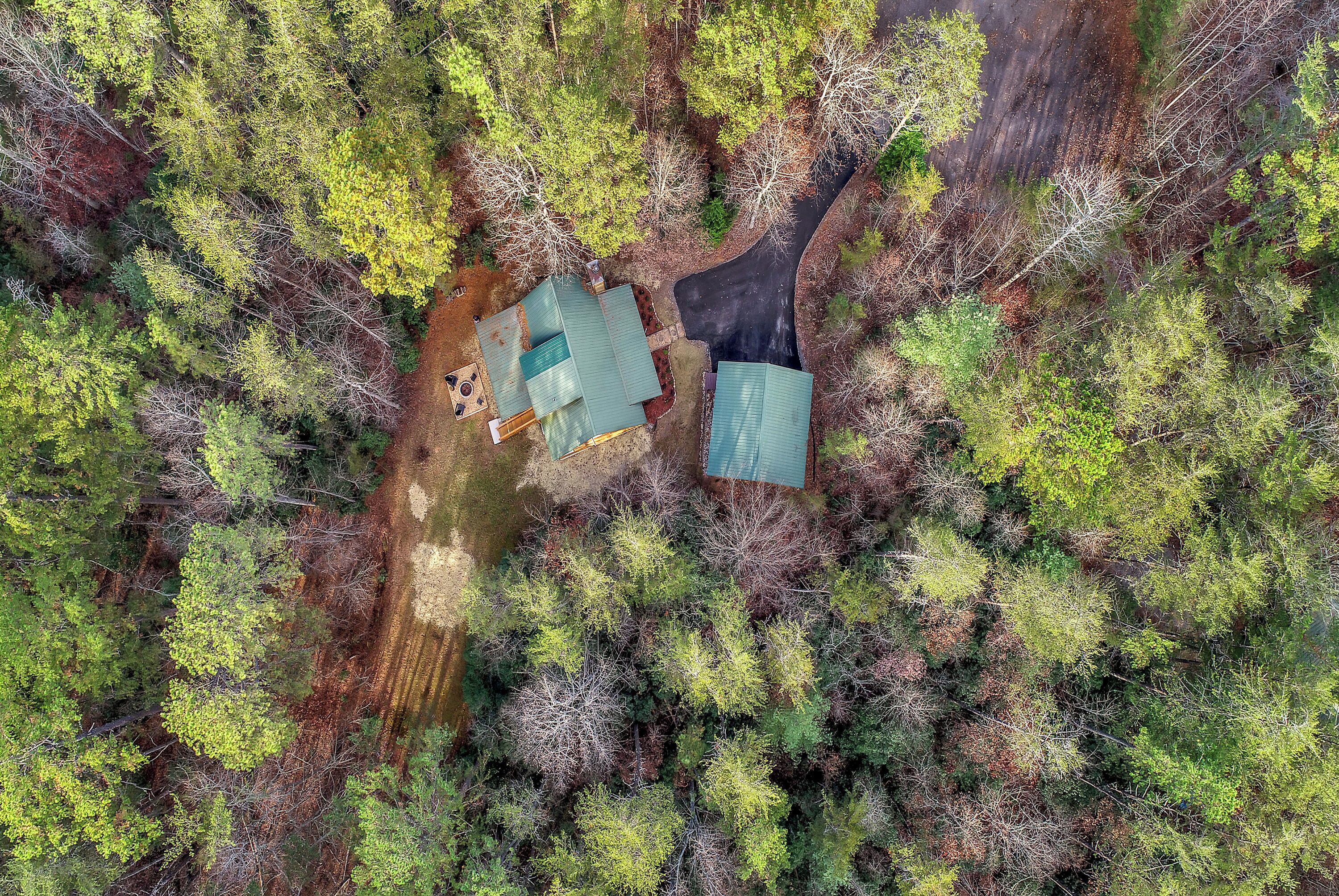 An aerial view of a property with two buildings surrounded by dense forest.