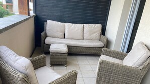 Een balkon met rieten meubels, waaronder een bank en twee stoelen.