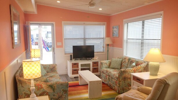 A living room with a sofa, armchair, TV stand, and lamps. - Venture Out #41 Gulf Loop 2bd, 1ba WITH GOLF CART!!! (Panama City)