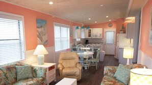 A compact living space with a sofa, armchair, and a dining table in the center. - Venture Out #41 Gulf Loop 2bd, 1ba WITH GOLF CART!!! (Panama City)