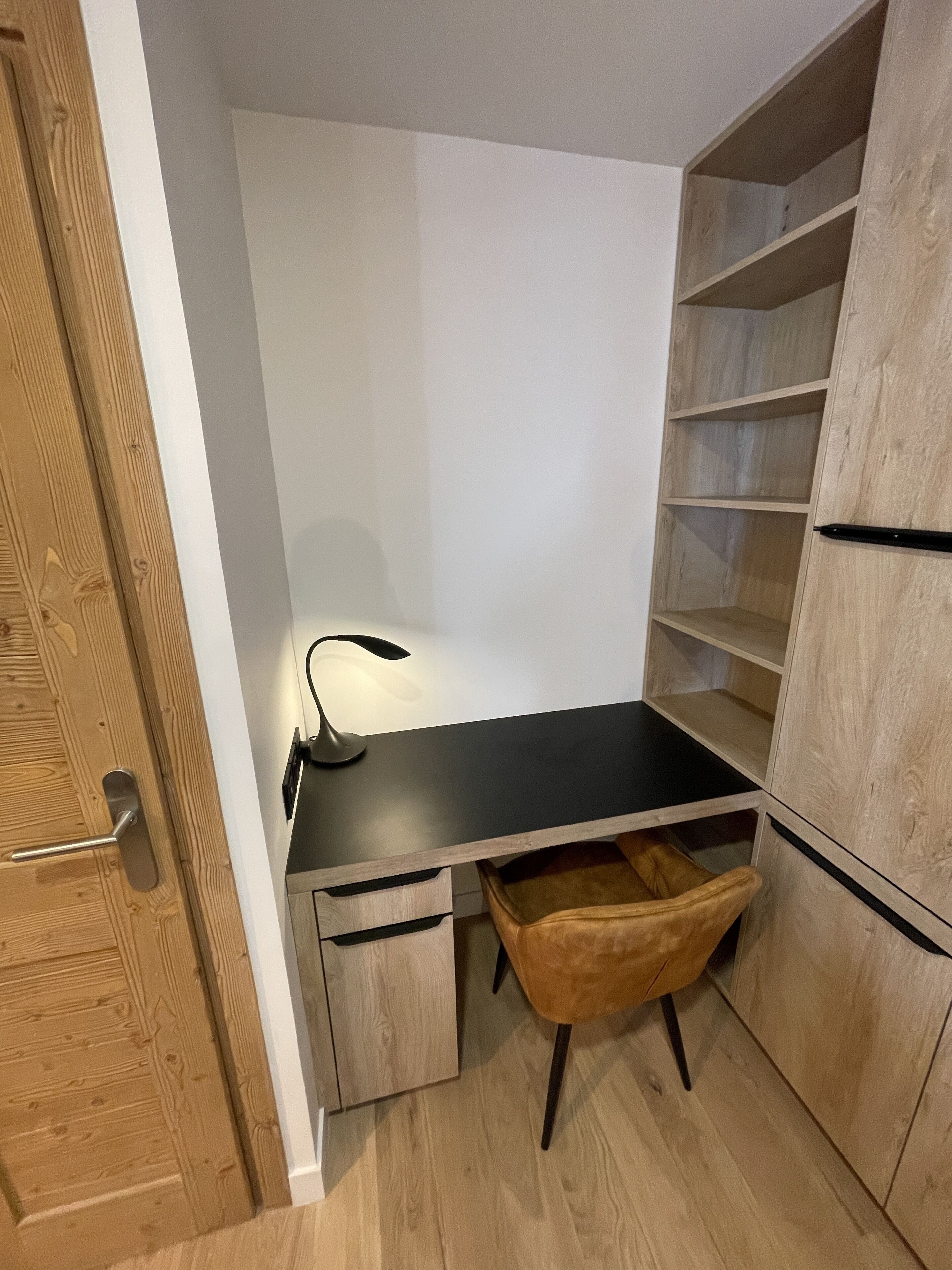Un petit espace bureau comprenant un bureau, une chaise et des étagères intégrées.