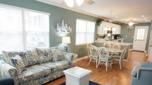 A living room with a sofa, a coffee table, and a dining area with chairs and a table. - Venture Out #79 Gulf Loop Comes With Golf Cart!!! (Panama City)