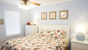 A bedroom with a bed, a nightstand, a lamp, a ceiling fan, and framed pictures on the wall. - Venture Out #79 Gulf Loop Comes With Golf Cart!!! (Panama City)