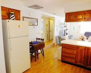 Enjoy meals in the kitchen with a central island and dining area, featuring a refrigerator, oven, and wooden table with chairs.