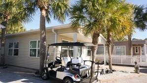 A single-story mobile home with a beige exterior, a covered porch, and a golf cart parked in front. - Venture Out #79 Gulf Loop Comes With Golf Cart!!! (Panama City)