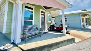 Een gelijkvloers huis met een overdekte veranda, een golfkar en een bank.